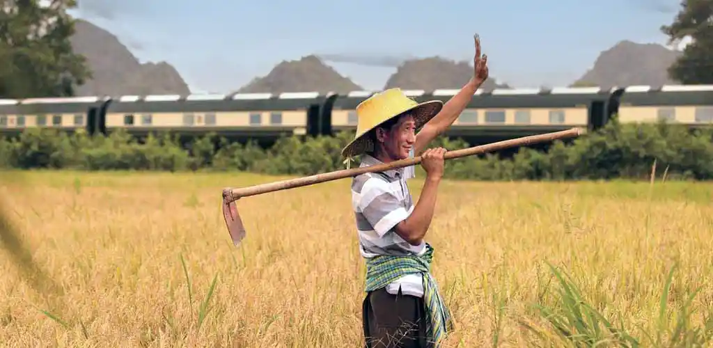 Eastern Oriental Express luxury train passing farmer in Thailand