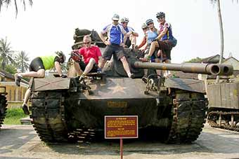 Old military tank with cyclists in Hue, Vietnam on VeloAsia cycling tour.