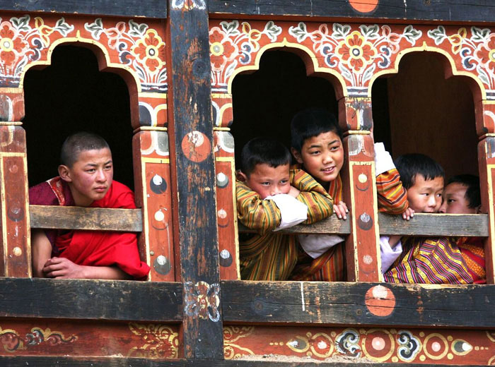 Student monks in Bhutan peer from monastery window