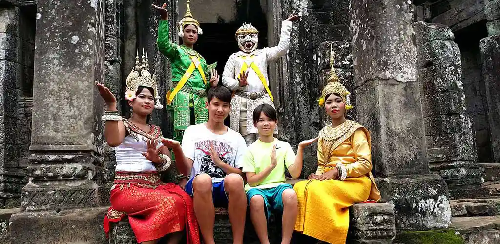 Family posing at Angkor temple with tradtional dancers in Cambodia