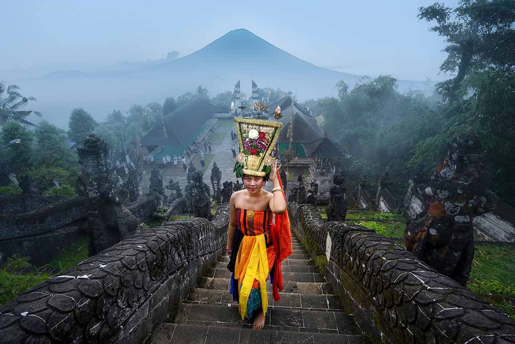 Woman in traditional dress before volcano in Bali