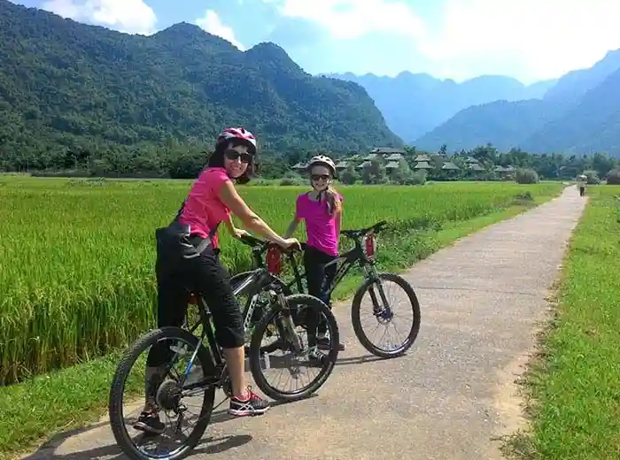 Family touring by bicycle in North Vietnam countryside.