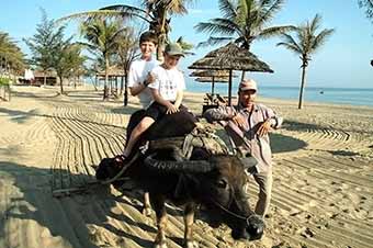 Boys riding water buffalo during family tour of Vietnam